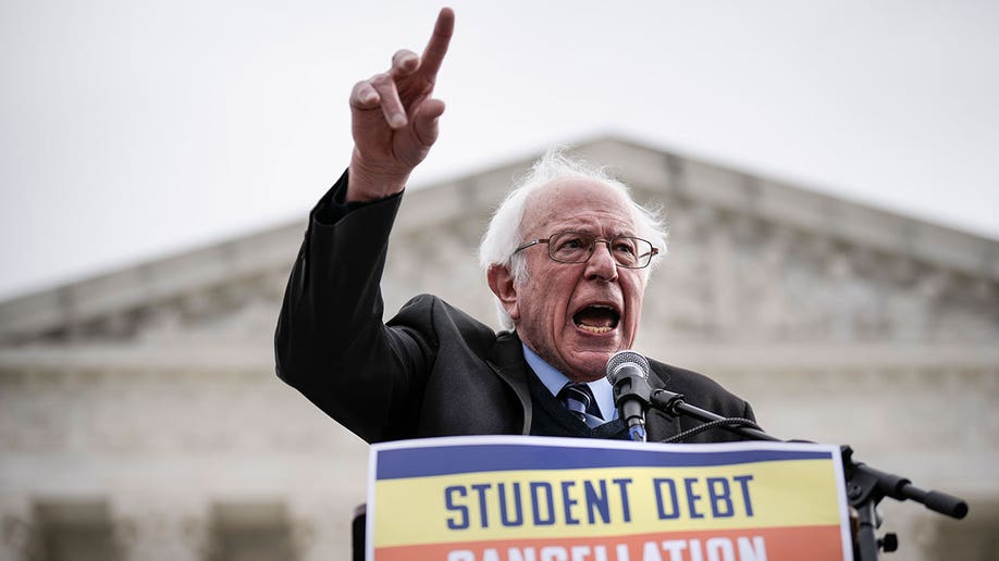 Sen. Bernie Sanders raises hand during student debt rally