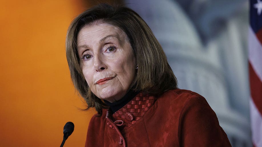 Nancy Pelosi wears maroon outfit and speaks into mic