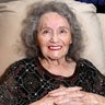 Gloria Dea sits on a chair at her home