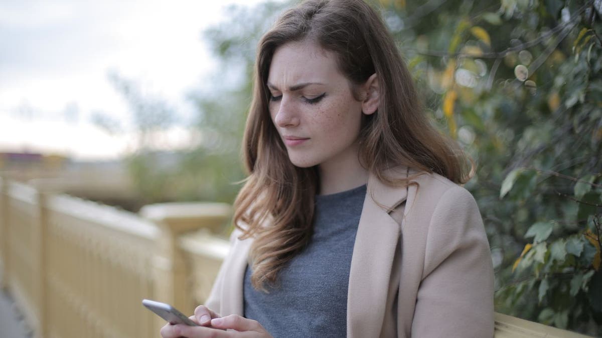 Woman looking at her phone with a confused look.