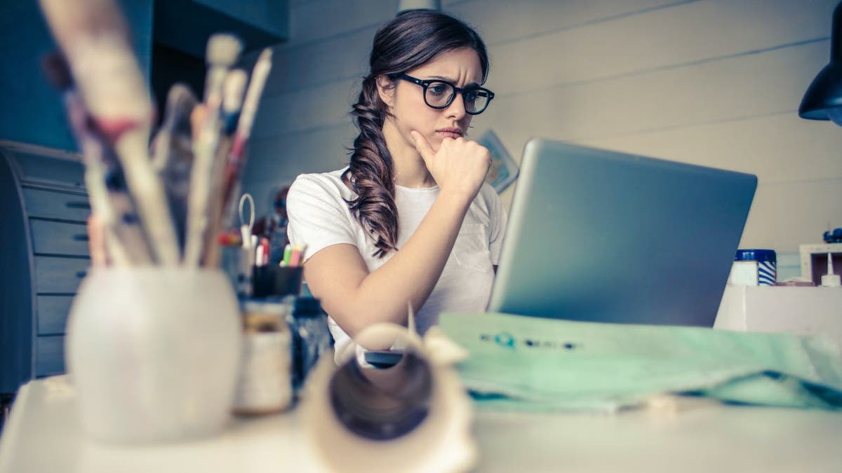 Woman wears glasses and looks stressed while at her computer