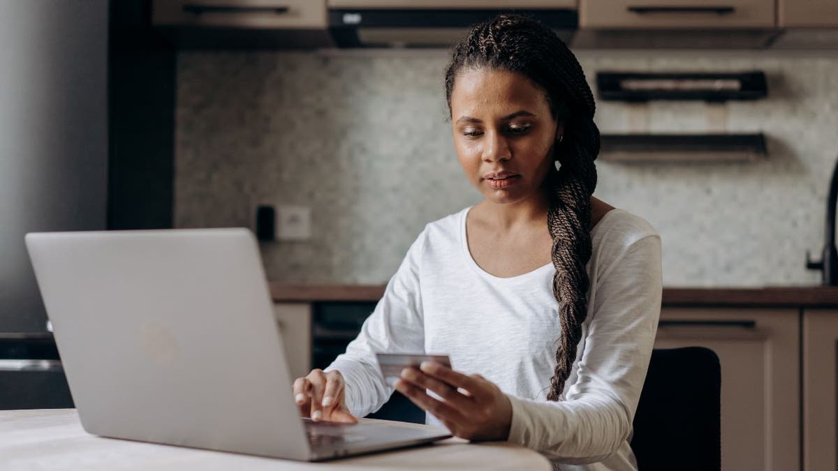 Woman holding a credit card and typing into her laptop.