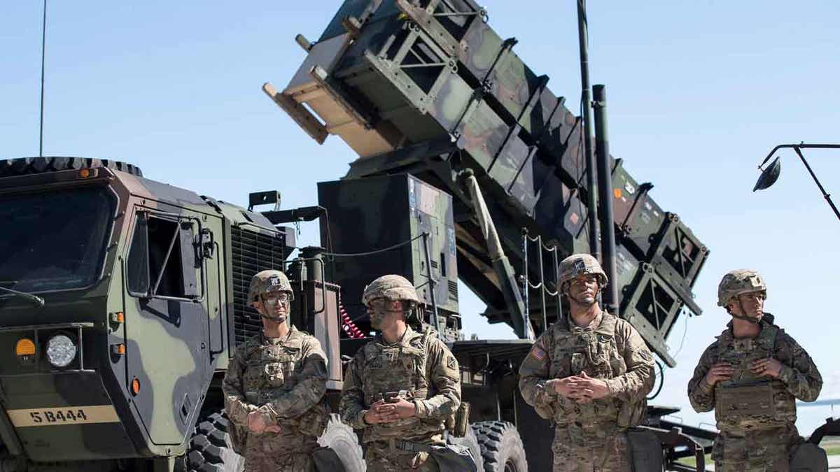 Members of US 10th Army Air and Missile Defense Command stands next to a Patriot