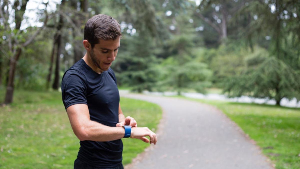 Man taking a break from running on a trail to check his smartwatch.