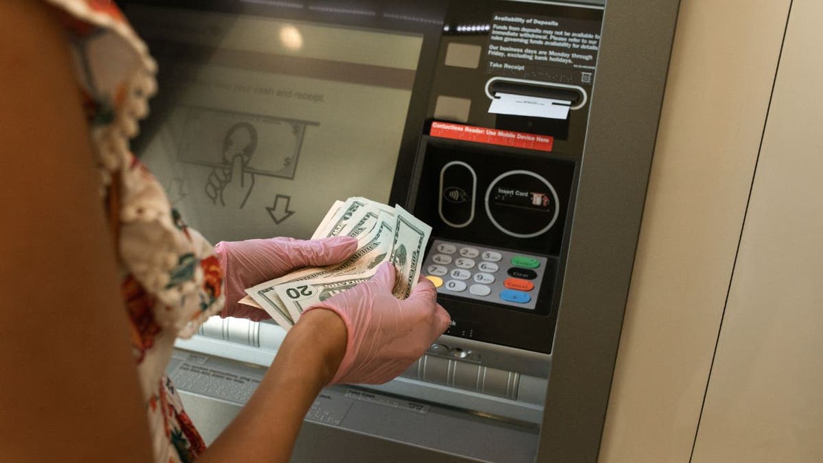 Woman holding cash in front of an ATM