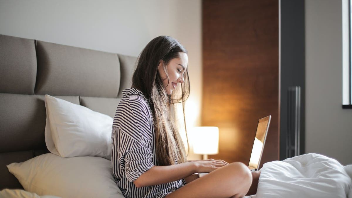 woman sitting on bed on laptop