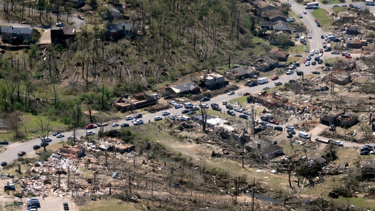 Cars line up along the road as cleanup continues from tornado damage in Arkansas