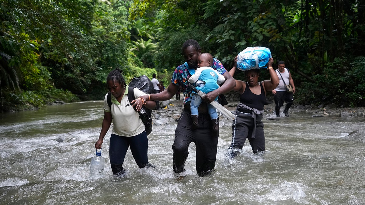 People helping walk through a river
