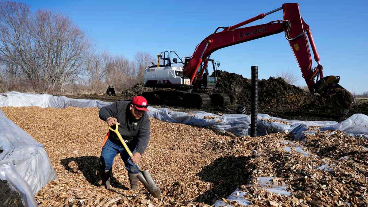 A worker shovels wood chips into a bioreactor