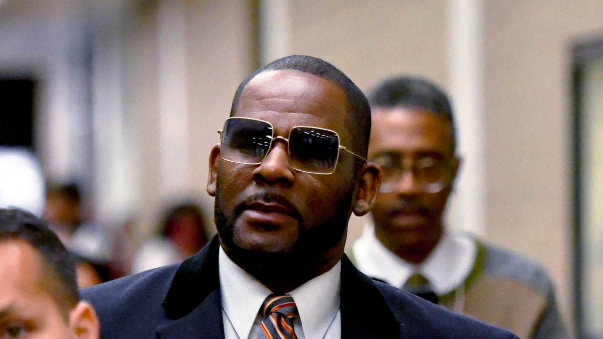 R Kelly lleva un abrigo azul y una corbata roja fuera del juzgado