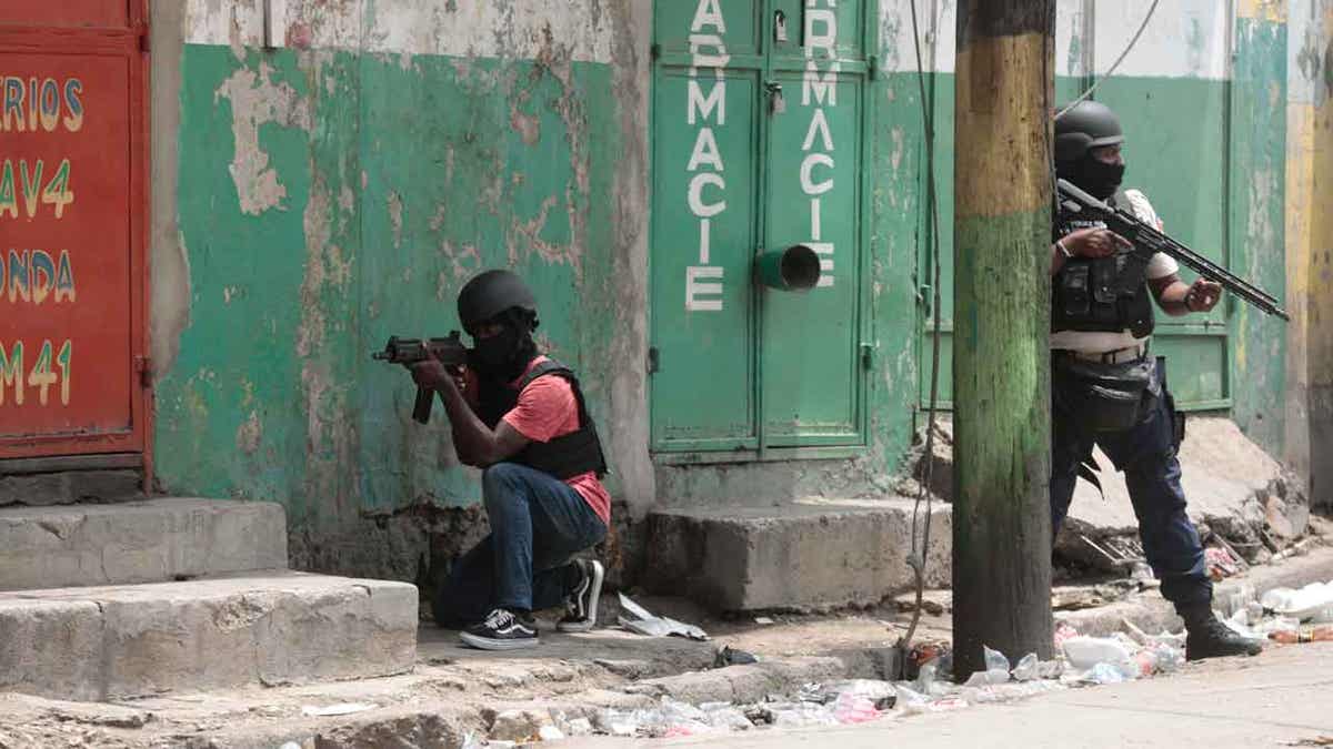 Police officers take cover during an anti-gang operation in Haiti