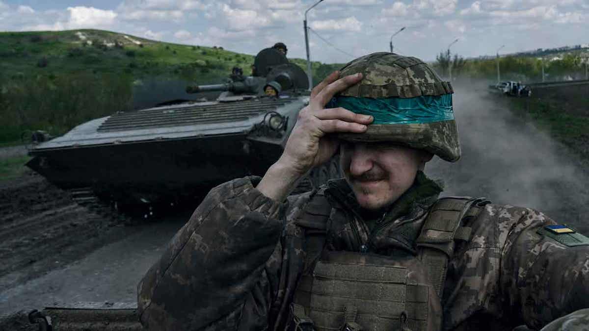 A Ukrainian soldier holds his helmet 