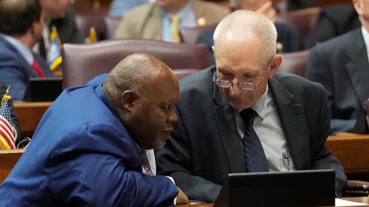 Rep. Greg Porter, left, talks with Rep. Jeff Thompson speaks at the Statehouse on April 27, 2023, in Indianapolis, Indiana. Thompson has defended the expansion of the voucher program.
