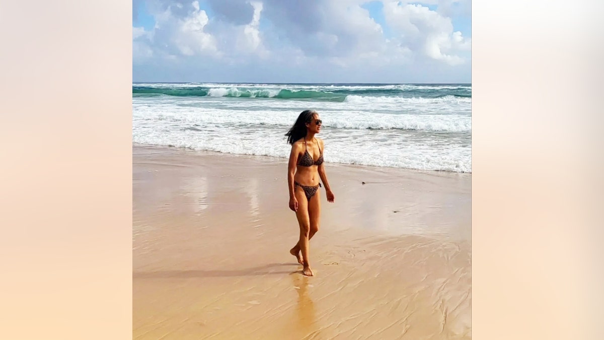 Nina Cash walking on the beach in a bikini