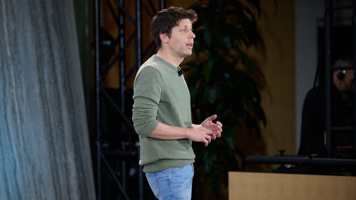 Sam Altman standing in green shirt, jeans