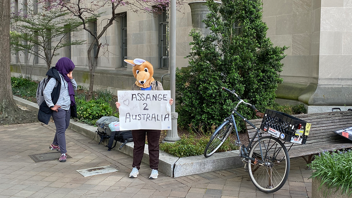 Woman in kangaroo mask holding sign in support of Julian Assange