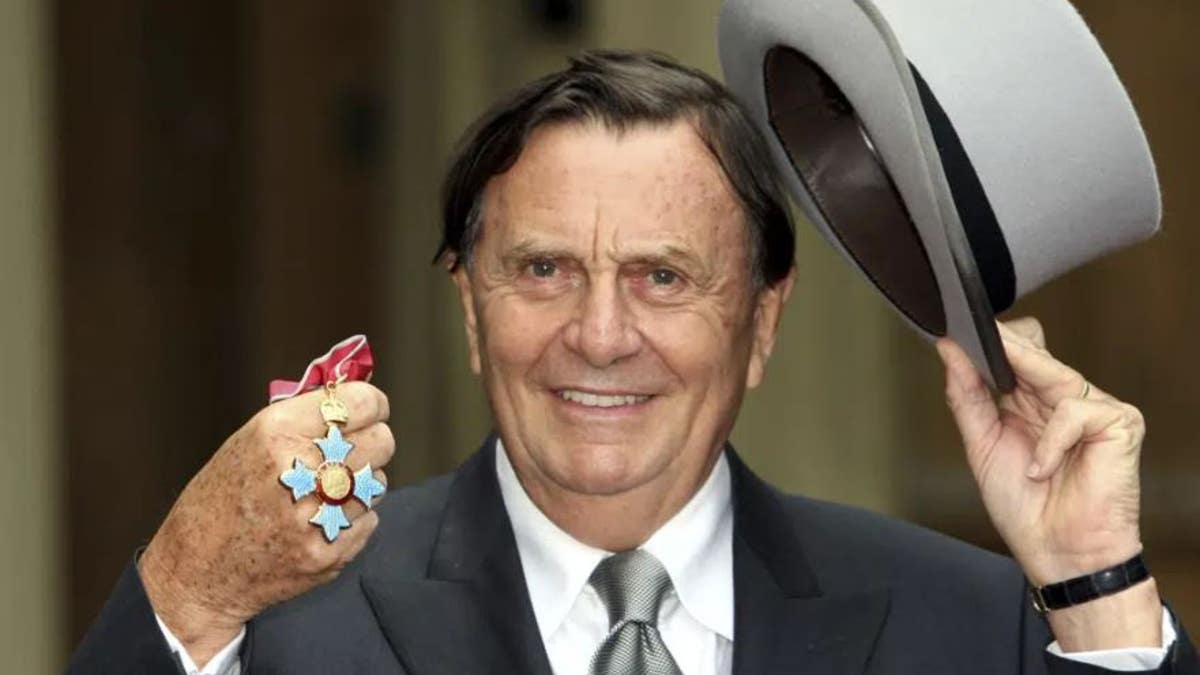 Barry Humphries poses pictures after he received his Most Excellent Order of the British Empire from Britain's Queen Elizabeth II