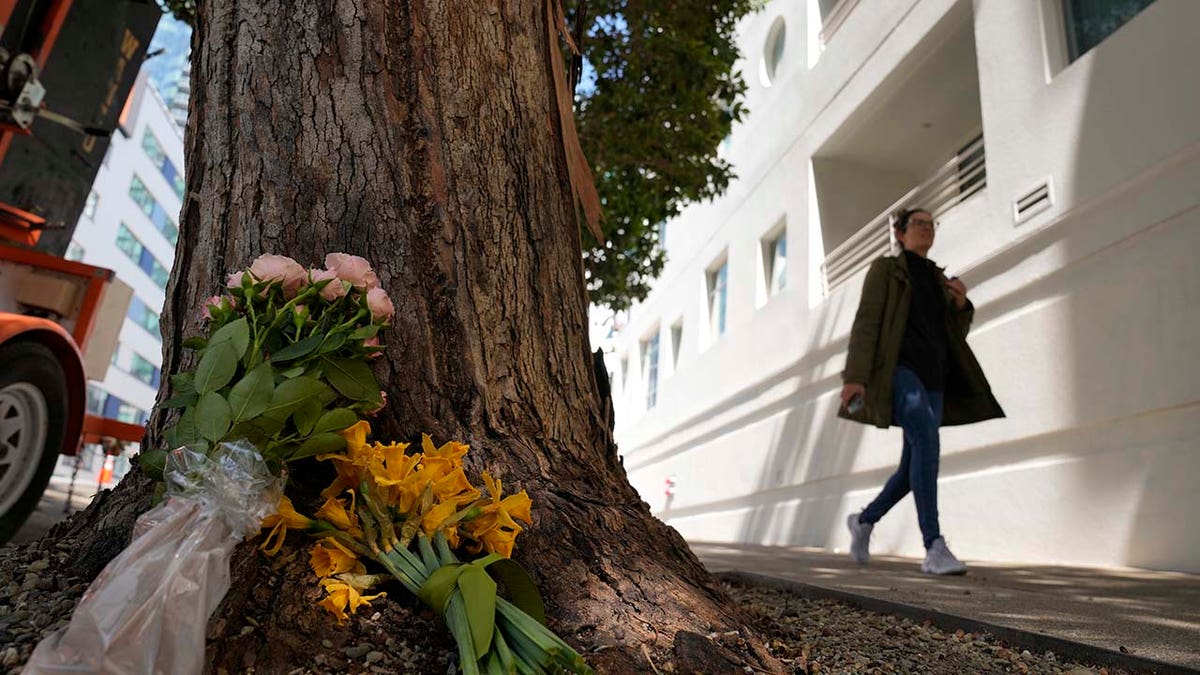 A woman walks past flowers left outside an apartment building where a technology executive was fatally stabbed
