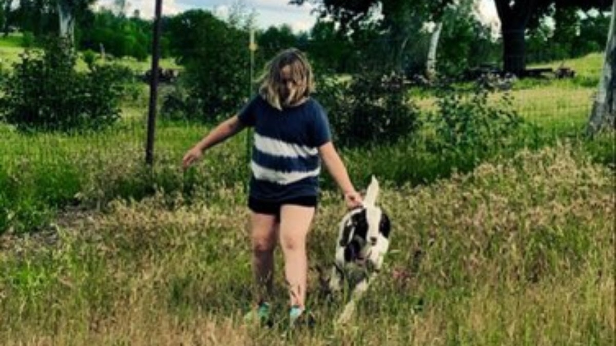 Jessica Long's daughter walking in field with Cedar the goat