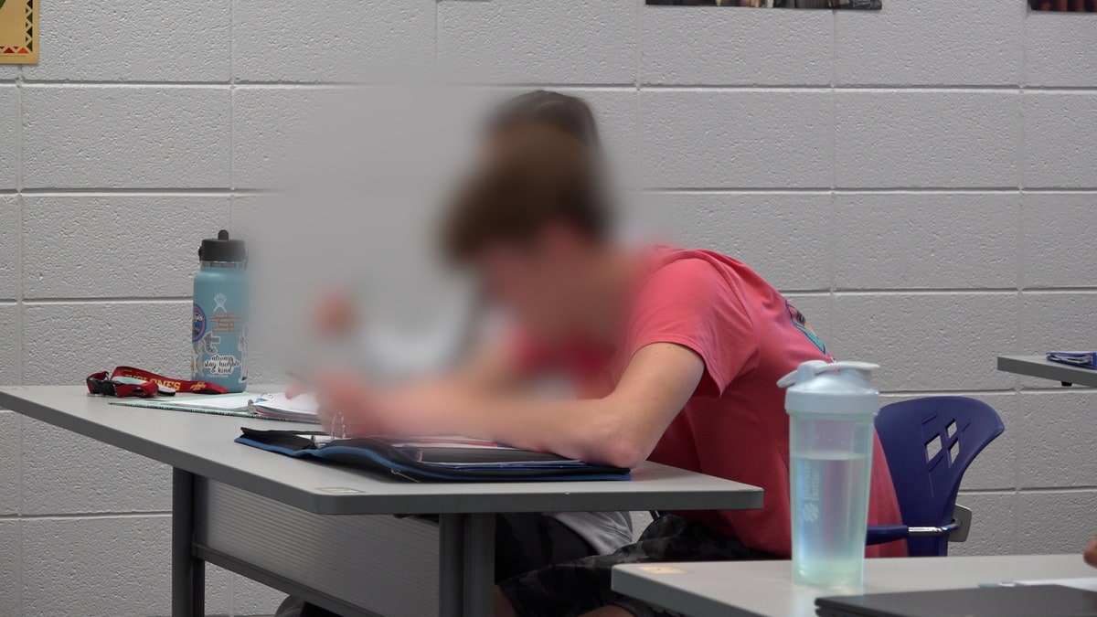 High school students have their heads down writing on paper