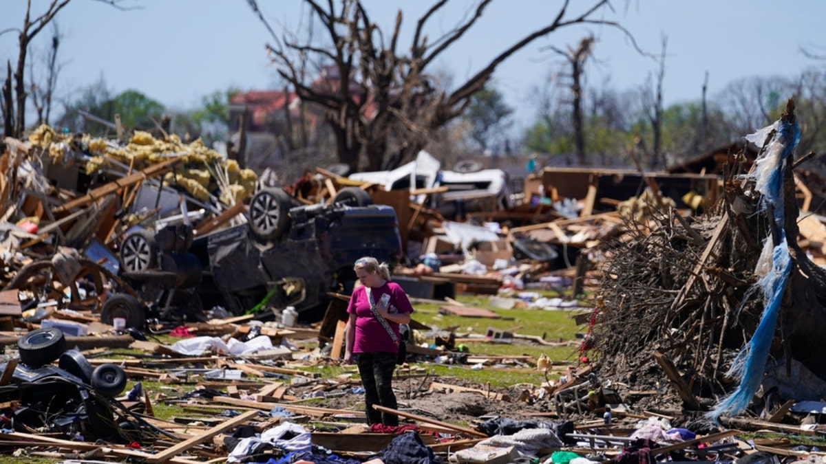 A woman walks near an uprooted tree in Mississippi