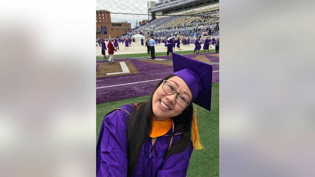 Woman posing with her cap and gown and a graduation.