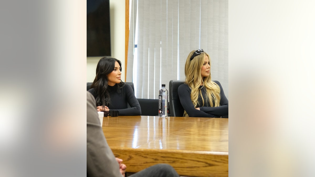 Kim and Khloe Kardashian listen at a round table
