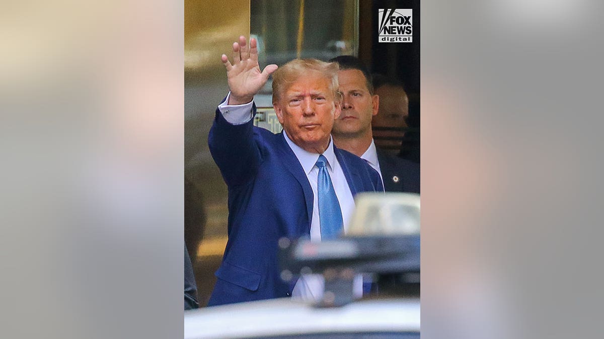 Donald Trump waving at the crowd as he leaves for his deposition.