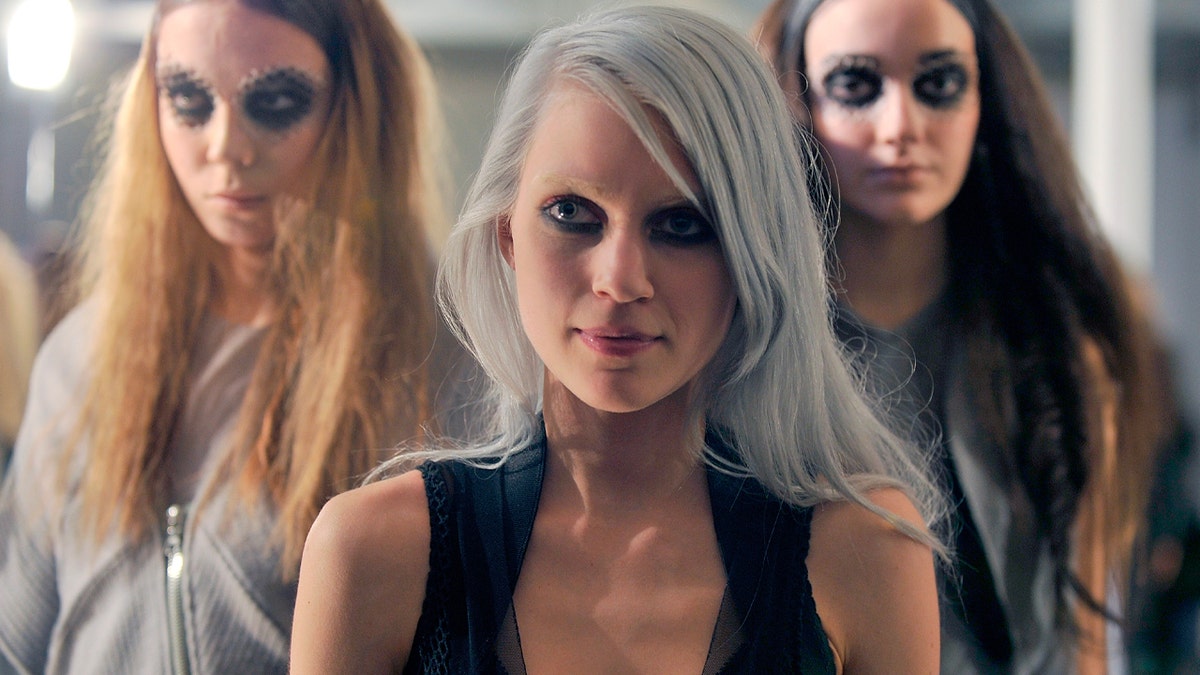 Fashion designer Katie Gallagher stands in front of two of her models