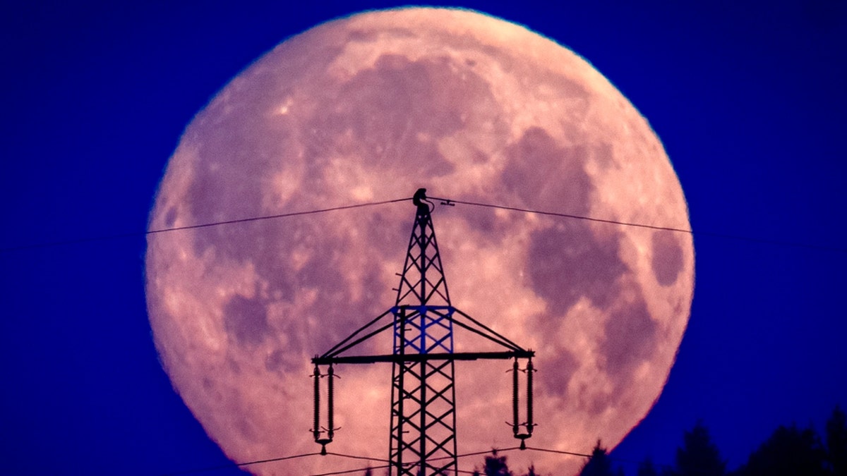The moon sets behind a power pole outside Frankfurt, Germany