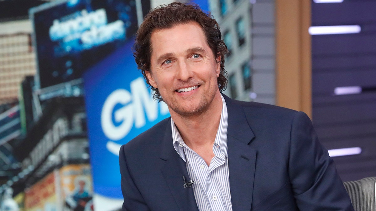 Matthew McConaughey in a blue striped shirt and navy blazer jacket smiles while on GMA