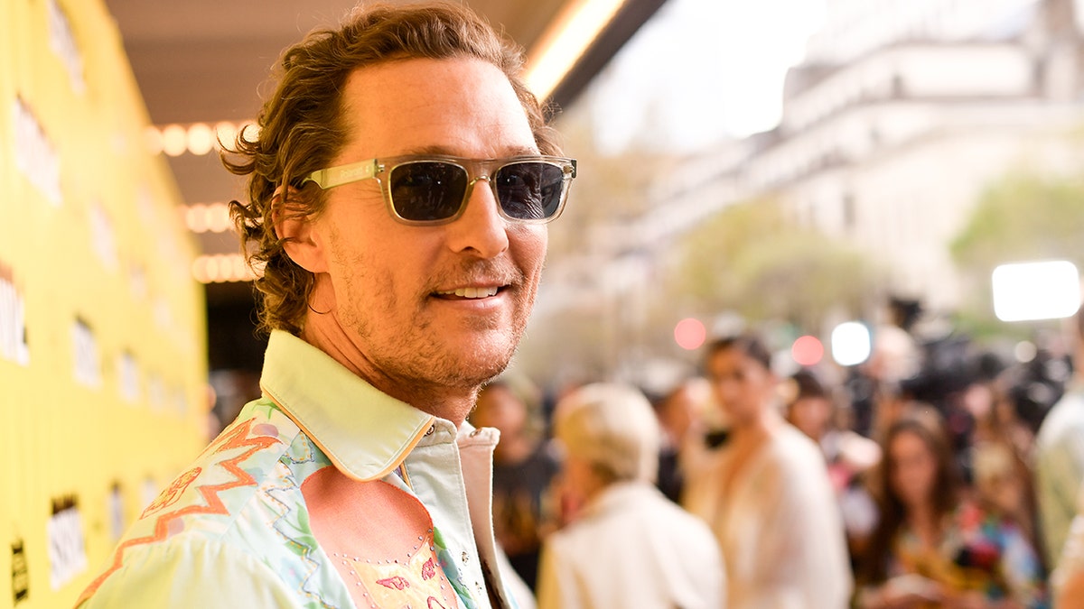 Matthew McConaughey wears a printed multi-colored shirt at SXSW and smiles at the camera with sunglasses on