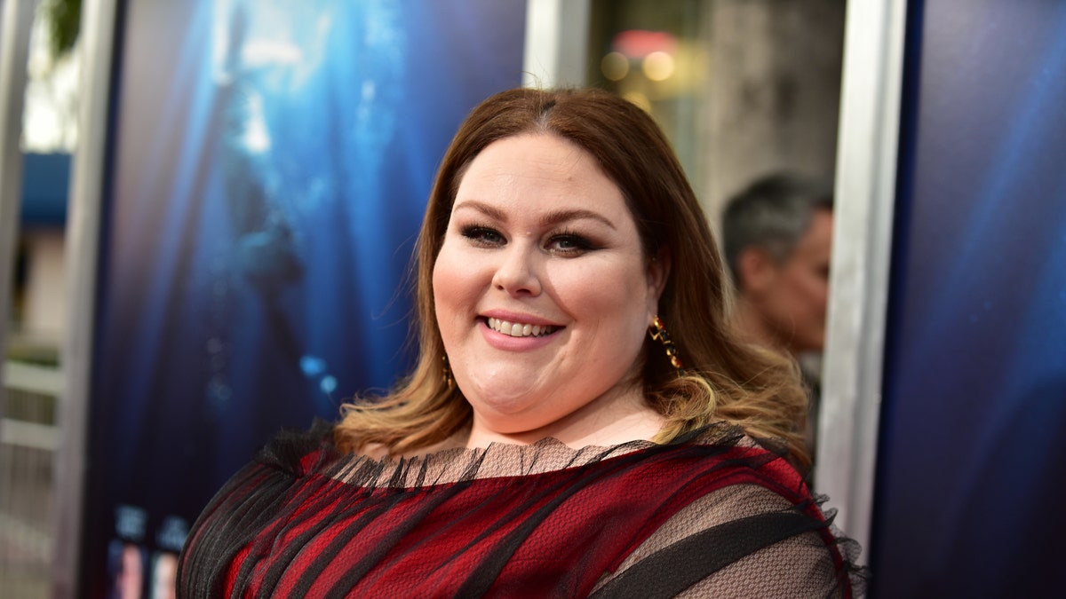 Chrissy Metz in a red and black dress smiling on the red carpet