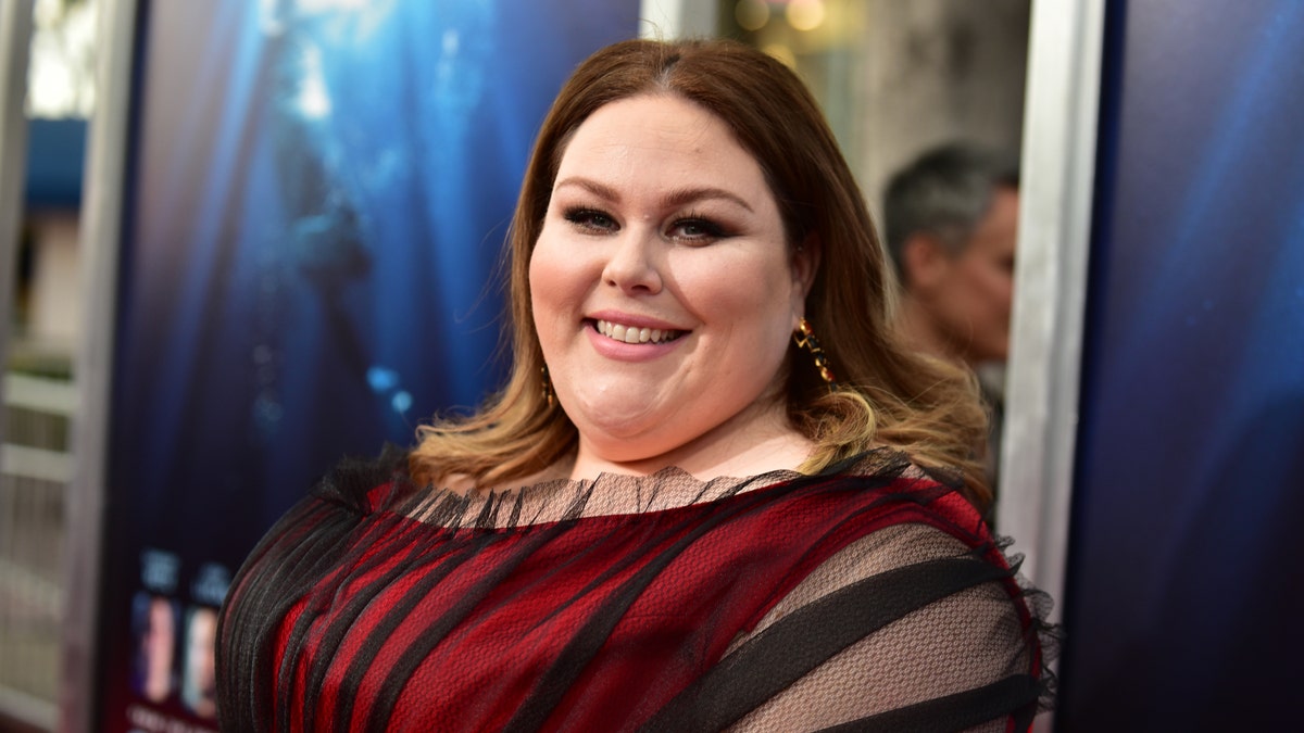 Chrissy Metz in a red and black dress smiling on the red carpet