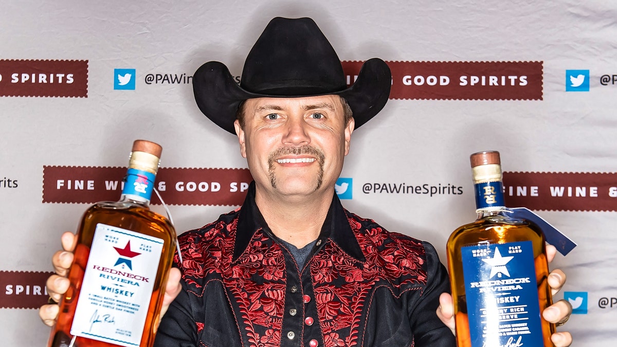 John Rich holding up bottles of his Redneck Riviera whiskey