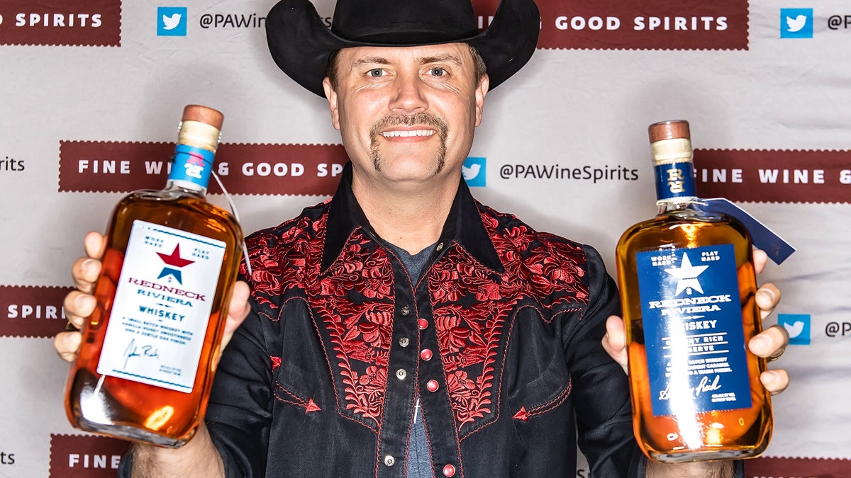 John Rich holding up bottles of his Redneck Riviera whiskey