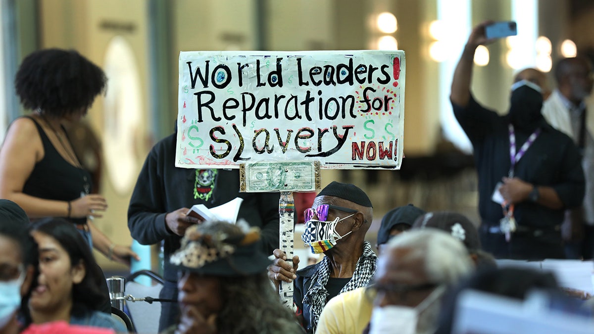 LA resident holds up sign demanding reparations for slavery 