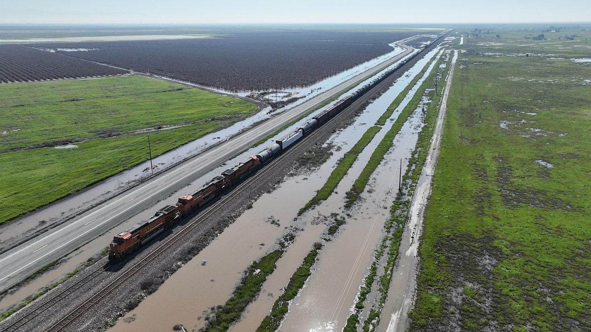 Allensworth, CA, Saturday, March 18, 2023 - A freight train travels past flooded land along Hwy 43, just north of Allensworth where residents are not waiting for government agencies to fortify a vulnerable levy in an effort to prevent floodwaters from inundating their community. (Robert Gauthier/Los Angeles Times via Getty Images)