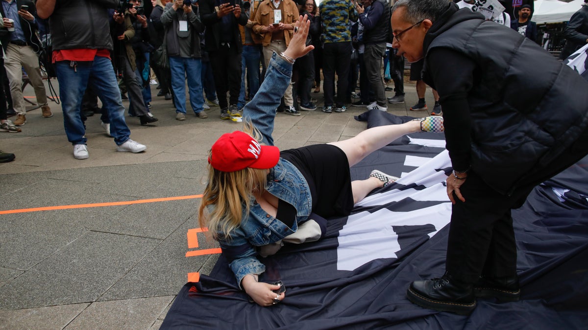 NEW YORK, NY - APRIL 04: A Trump supporter removes a banner from anti-Trump protesters outside the Manhattan Criminal Courthouse on April 04, 2023 in New York City. Former President Donald Trump is scheduled to travel to New York City today with an expected arraignment tomorrow at court following his indictment by a grand jury. The indictment is sealed but a grand jury has heard evidence of money paid to adult film actress Stormy Daniels during Trump's 2016 presidential campaign. (Photo by Kena Betancur/Getty Images)