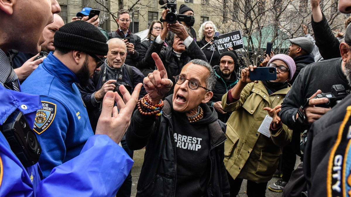 A protestor, center, speaks with members of the New York City Police Department (NYPD) outside criminal court in New York, US, on Tuesday, April 4, 2023. Trump, the first former US president to be indicted, will plead not guilty when he appears in a Manhattan state court Tuesday to face criminal charges, his defense lawyer said. Photographer: Stephanie Keith/Bloomberg via Getty Images