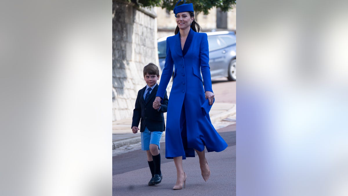 Prince George in blue blazer and shorts walks with Kate Middleton in blue coat dress