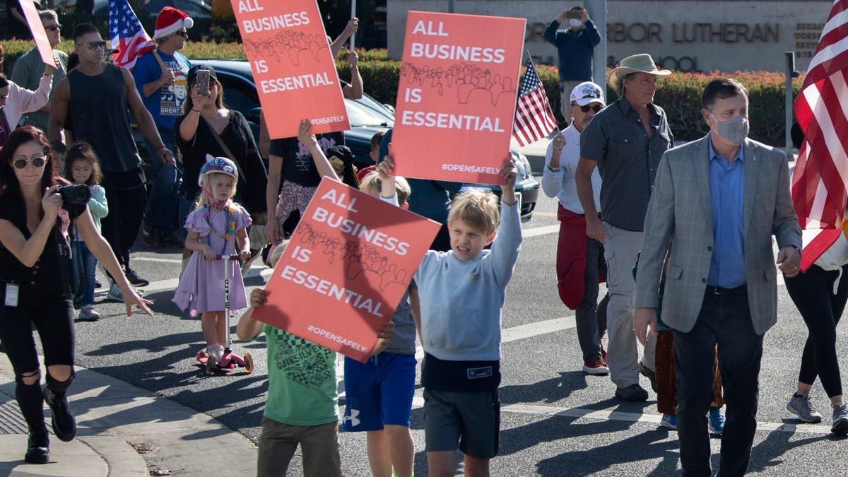 Orange County Supervisor Don Wagner, right, joins a group of protesters