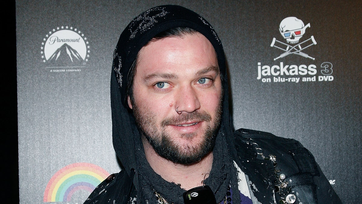 Bam Margera in a black hoody looks off in distance