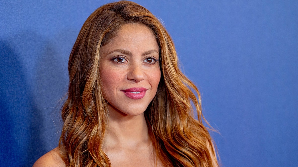 Shakira wears pink lipstick and has peachy makeup on at NBCUniversal Upfronts in New York City with long orange/amber hair