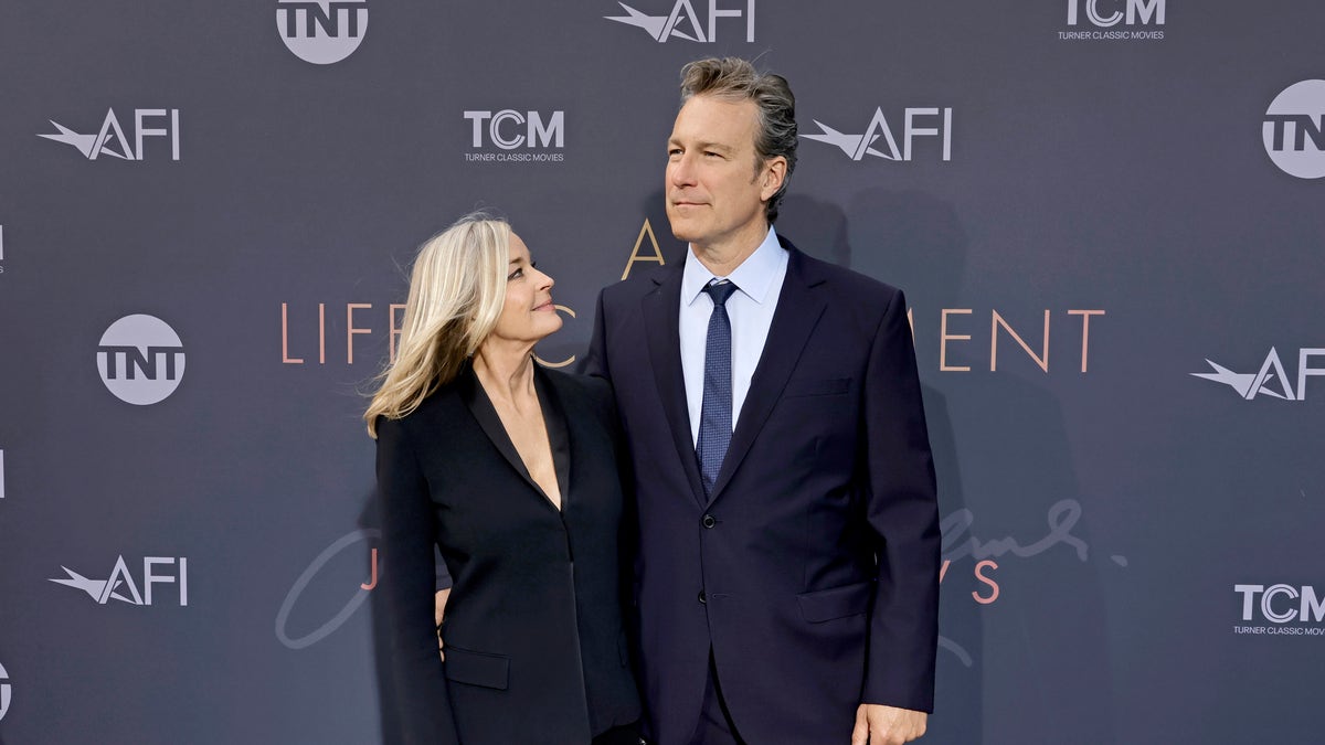 Bo Derek with John Corbett both wearing suit jackets on the red carpet