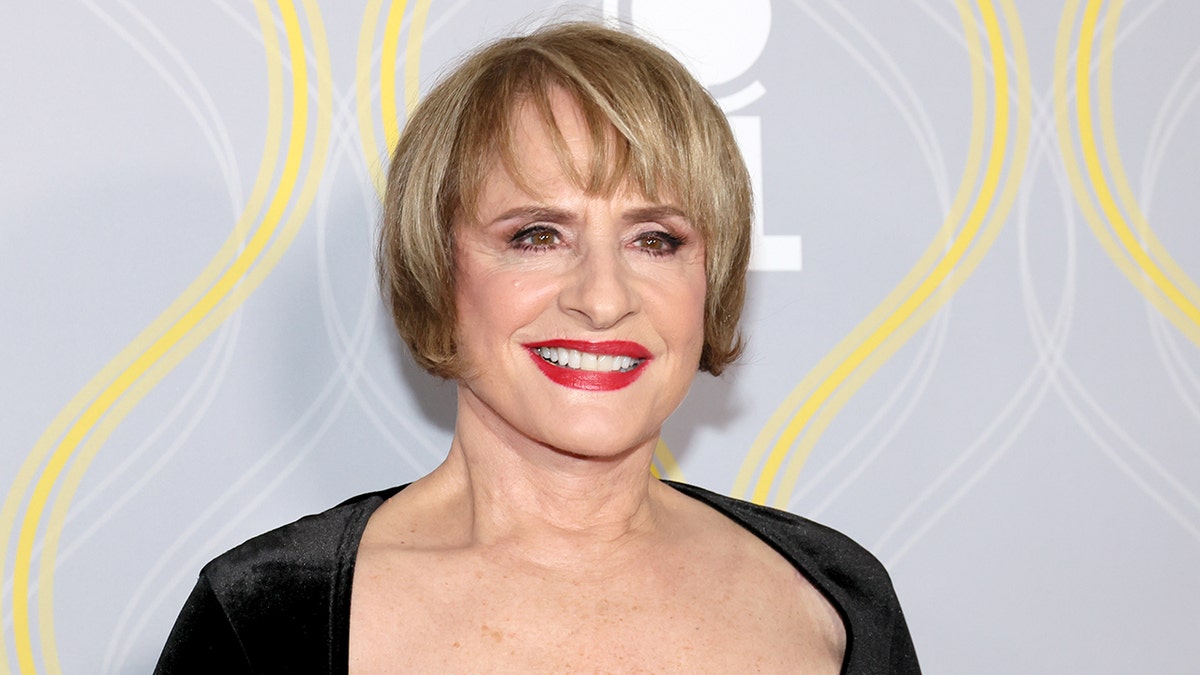 Patti LuPone smiles on the Tony Awards red carpet in a square cut, black dress and red lipstick