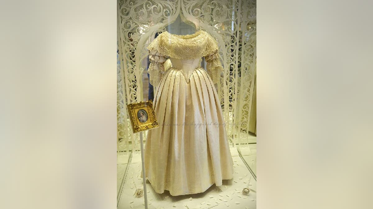 Queen Victoria's wedding dress encased in glass display case during an exhibition.
