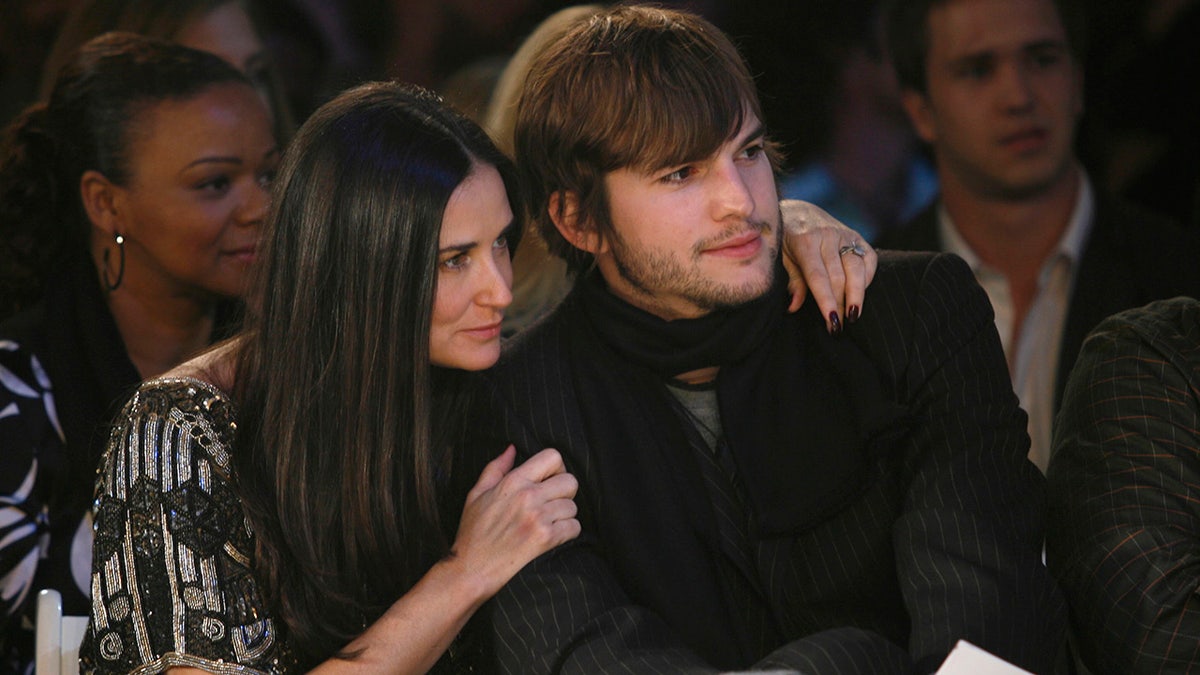 Demi Moore throws her arm around Ashton Kutcher at a fashion show