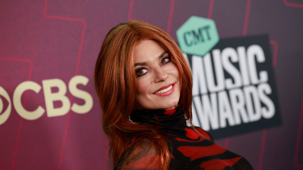 Shania Twain wears a red wig and looks over her shoulder on CMT Music Awards red carpet