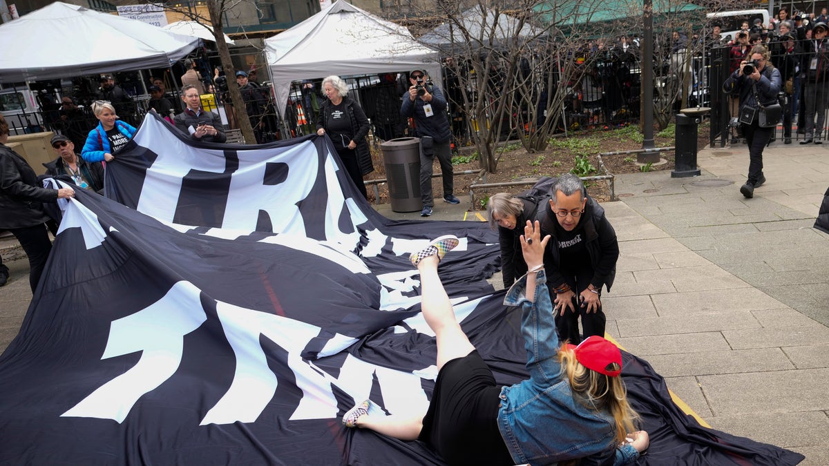 NEW YORK, NEW YORK - APRIL 04: A supporter of former U.S. President Donald Trump tumbles to the ground on top of a banner criticizing him outside the courthouse where Trump will arrive later in the day for his arraignment on April 4, 2023 in New York City. With his indictment, Trump will become the first former U.S. president in history to be charged with a criminal offense. (Photo by Drew Angerer/Getty Images)